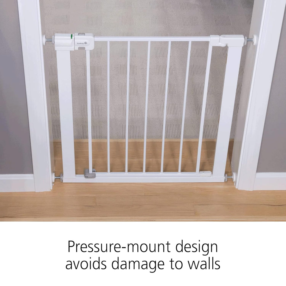 White pressure-mount baby gate on a wooden floor with text indicating it avoids wall damage.
